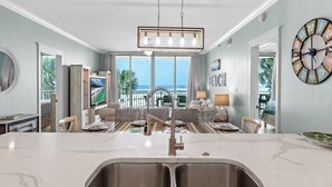 A spacious living area with a large kitchen island, a dining table, and a view of the ocean. - Waterscape B201 ~ Oceanfront 3BR ~ Amazing Gulf Views! (Fort Walton Beach)