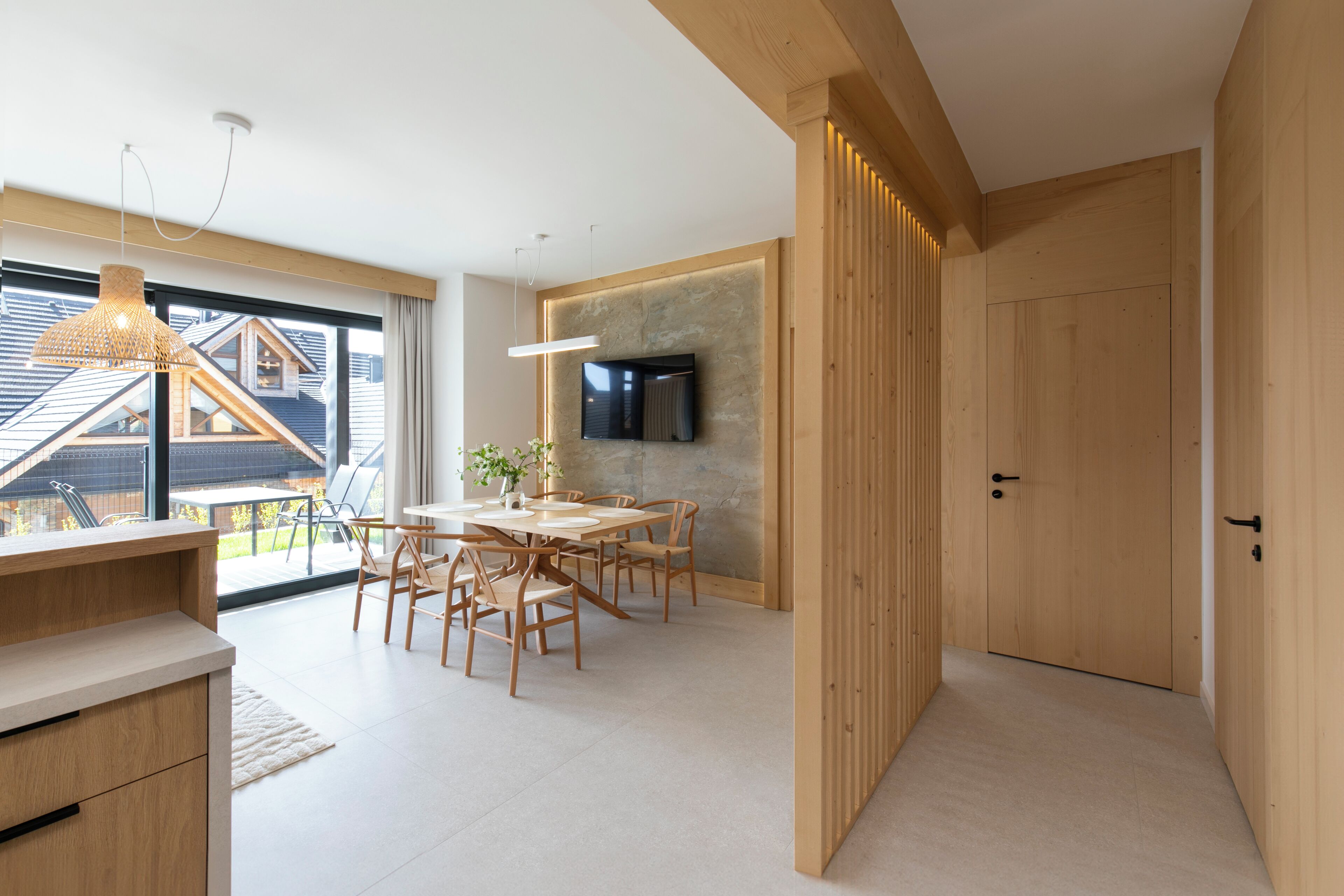 A modern interior with a dining area, wooden walls, and a TV mounted on the wall.