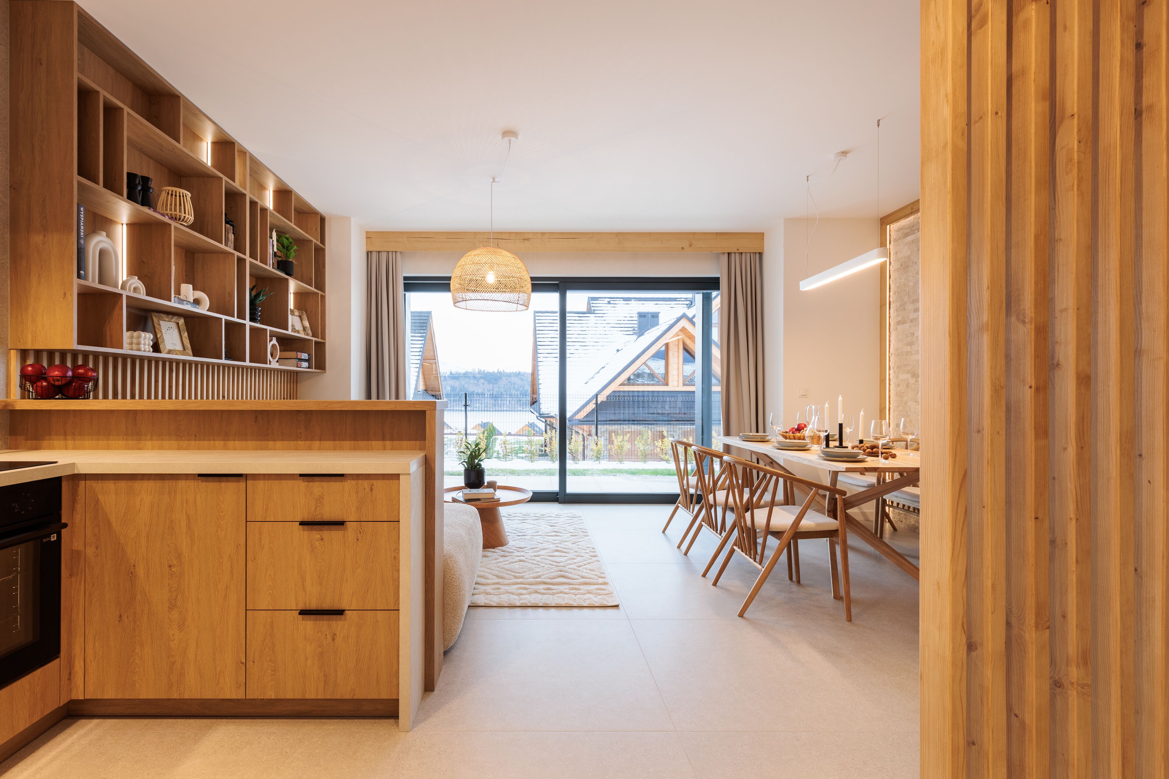Une cuisine moderne avec des meubles en bois et un coin repas agrémenté d’une grande fenêtre.