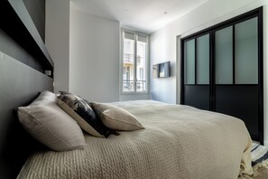 Ein Schlafzimmer mit einem großen Bett, einem Fernseher an der Wand und einem Fenster mit Blick nach draußen.