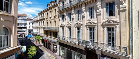 Une vue d’une rue où l’on aperçoit un immeuble abritant plusieurs commerces, dont un magasin KEITEL.