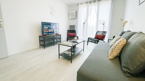 A modern living room with a sofa, a coffee table, a TV, and a chair.