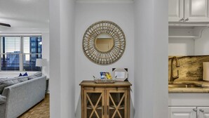 Un salón moderno con un sofá gris, un mueble de madera con puertas de cristal y un espejo decorativo en la pared.