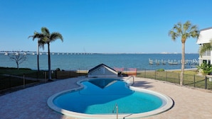 A swimming pool with a view of the sea and a distant bridge.