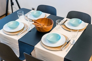 A neatly set dining table with blue and white plates, wooden bowls, and cutlery. - Renovato Prestige (Porto)