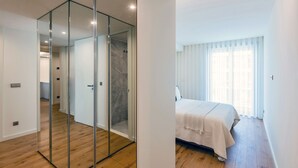 Una camera da letto moderna con un letto grande, una parete divisoria in vetro e un pavimento in legno.