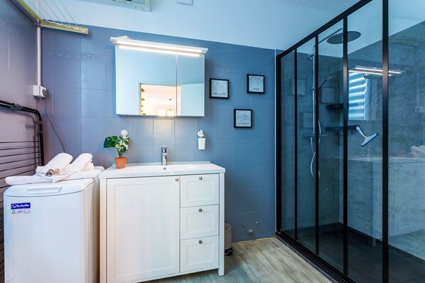 Un bany modern amb un moble de bany blanc, un mirall gran i una cabina de dutxa de vidre.