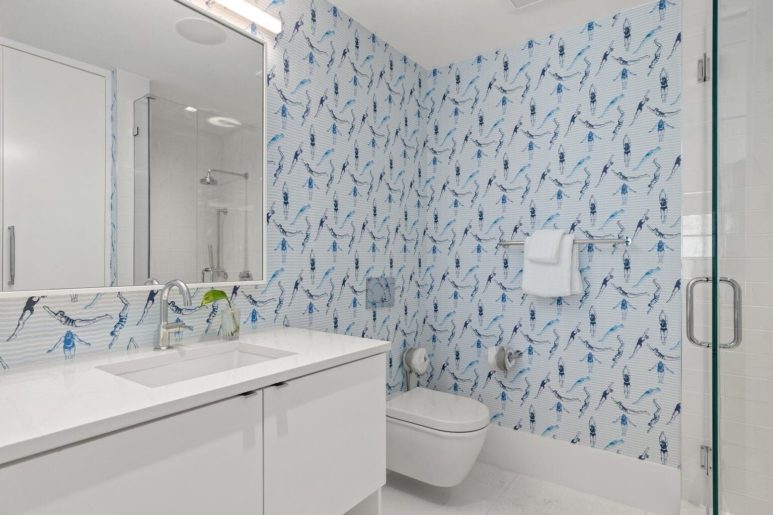 Une salle de bain moderne avec un lavabo blanc, une douche en verre et des toilettes.