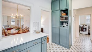 A kitchen with teal cabinets, a microwave, and a washing machine.