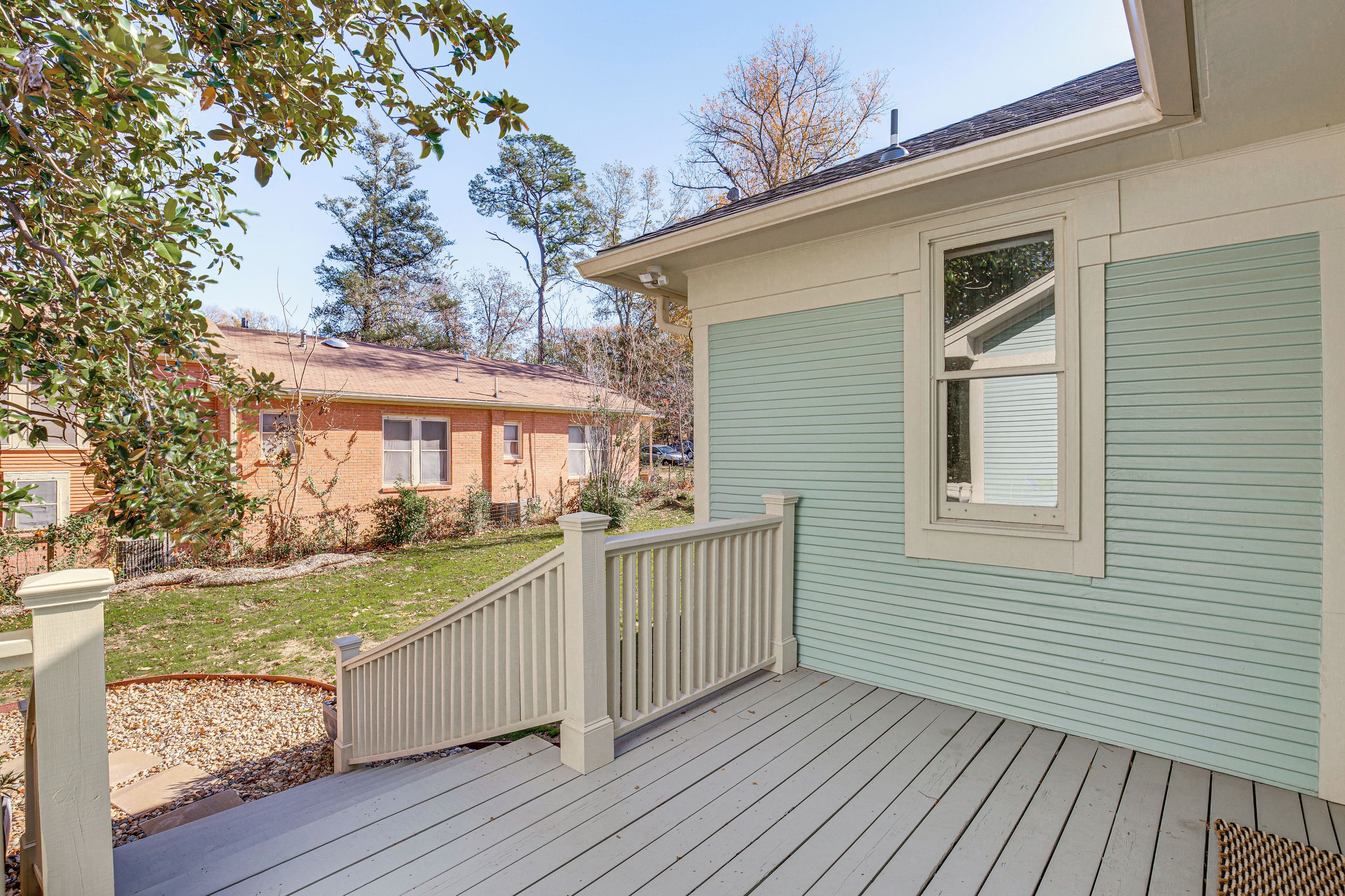 A house with a wooden deck, a small porch, and a light green exterior.