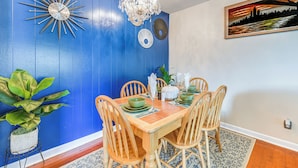 Een eetkamer met een blauwe wand, een kroonluchter en een schilderij.