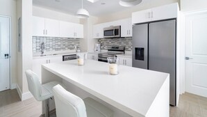 A modern kitchen with white cabinets, stainless steel appliances, and a central island with bar stools.