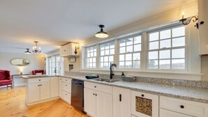 A spacious kitchen with white cabinetry, a granite countertop, and a large window providing natural light. - Oceanfront Mid-coast Maine Home w/ Private Beach! (Stockton Springs)