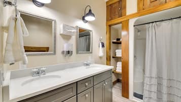 A bathroom with two sinks, a mirror, a shower, and wooden cabinets.