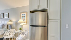 Eine moderne Küche mit Edelstahlkühlschrank, weißen Schränken und einem kleinen Essbereich mit weißen Stühlen und einem Tisch.