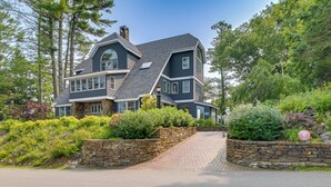 A large, two-story house with a stone entrance and a driveway leading to the front door. - The Beachhouse Retreat w/ Prescot Bay Views! (Stockton Springs)