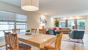 Uma sala de estar ampla com uma mesa de jantar de madeira, cadeiras, um sofá e uma mesinha de centro.