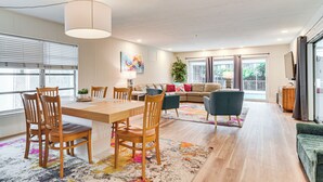 Uma sala de estar moderna com área de jantar, móveis de madeira e janelas amplas.