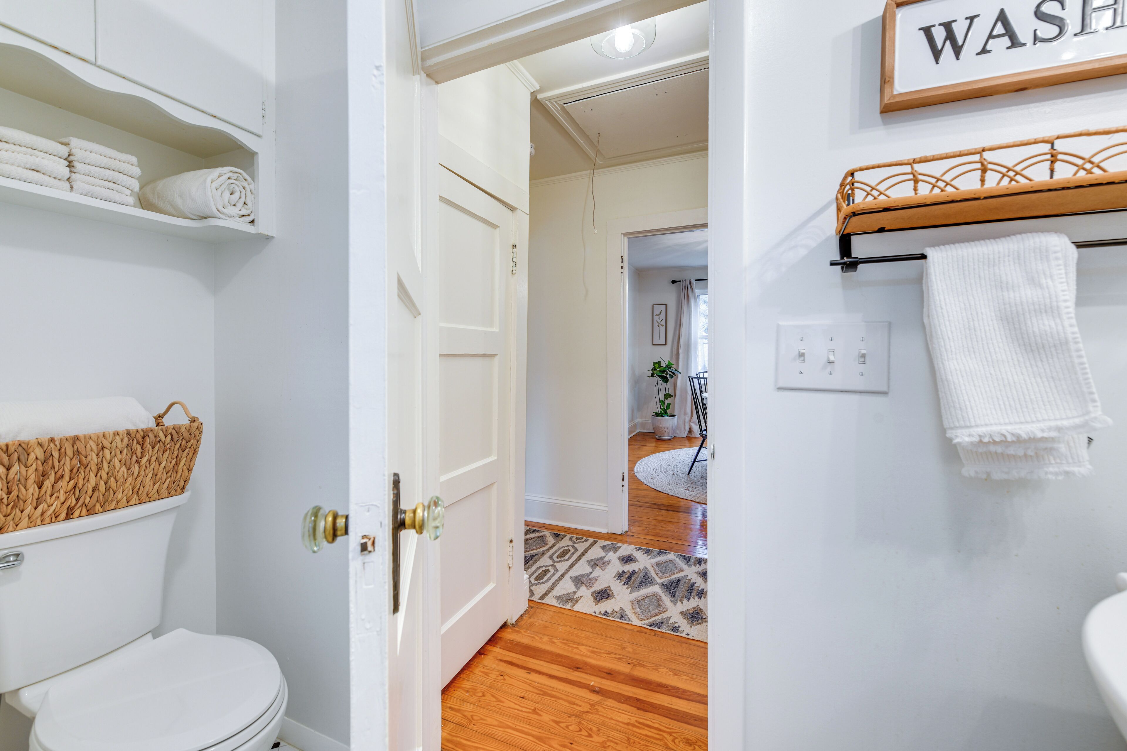 A bathroom with a toilet, a shelf with towels, and a wall-mounted towel rack.