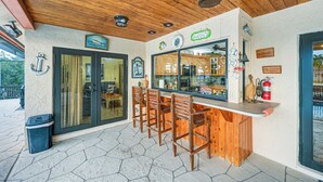 A bar area with wooden chairs, a counter, and a view of the interior through glass doors. - Marco Island Home w/ Private Pool & Water Views! (Marco Island)