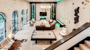 A spacious living area with a pool table, leather sofa, and a staircase. - Heated Pool: Tropical Townhome in Wheat Ridge (Wheat Ridge)