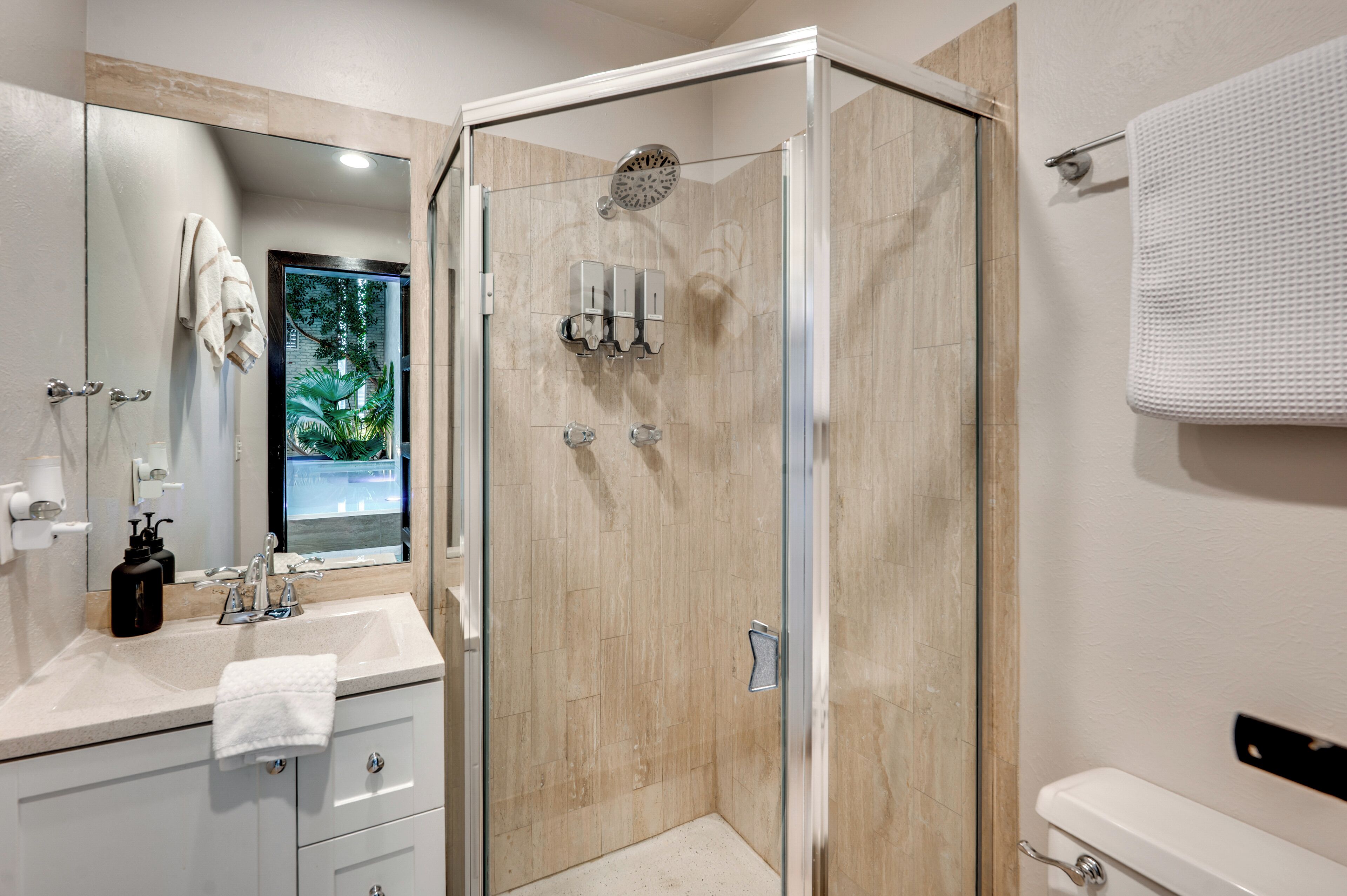 A modern bathroom with a glass-enclosed shower, a sink with a mirror, and a toilet.