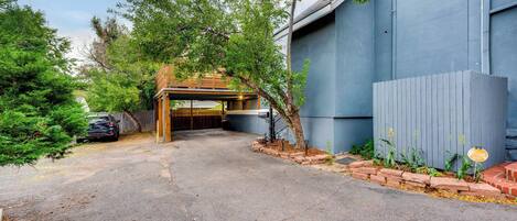 A driveway leading to a garage with a covered entrance, surrounded by trees and a brick pathway.