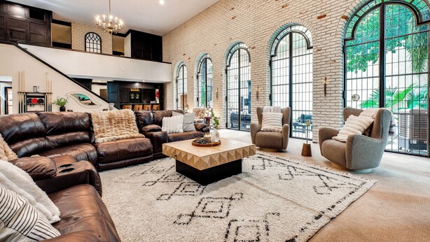 A spacious living area with a leather sofa, a coffee table, and a large window with arched designs. - Heated Pool: Tropical Townhome in Wheat Ridge (Wheat Ridge)