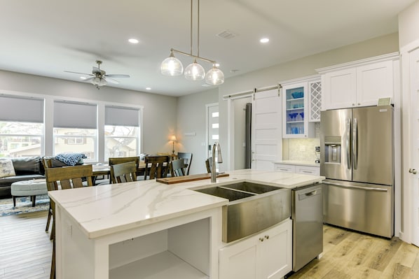 Una cocina moderna con una isla grande, electrodomésticos de acero inoxidable y muebles de cocina blancos.