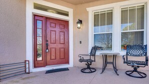 A front entrance with a red door, two metal chairs, and a small table. - Spacious Vacation Rental w/ Yard in Kissimmee! (Kissimmee)