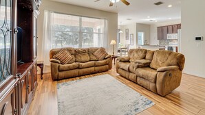 A living room with two brown sofas, a wooden floor, a ceiling fan, and a view to the outside. - Spacious Vacation Rental w/ Yard in Kissimmee! (Kissimmee)