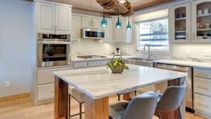 A modern kitchen with white cabinetry, stainless steel appliances, and a marble island. - Lakefront Townhome w/ Dock: 6 Mi to Blue Ridge! (Morganton)
