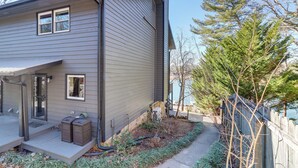 A modern two-story house with a covered porch, a small garden, and a wooden fence. - Lakefront Townhome w/ Dock: 6 Mi to Blue Ridge! (Morganton)