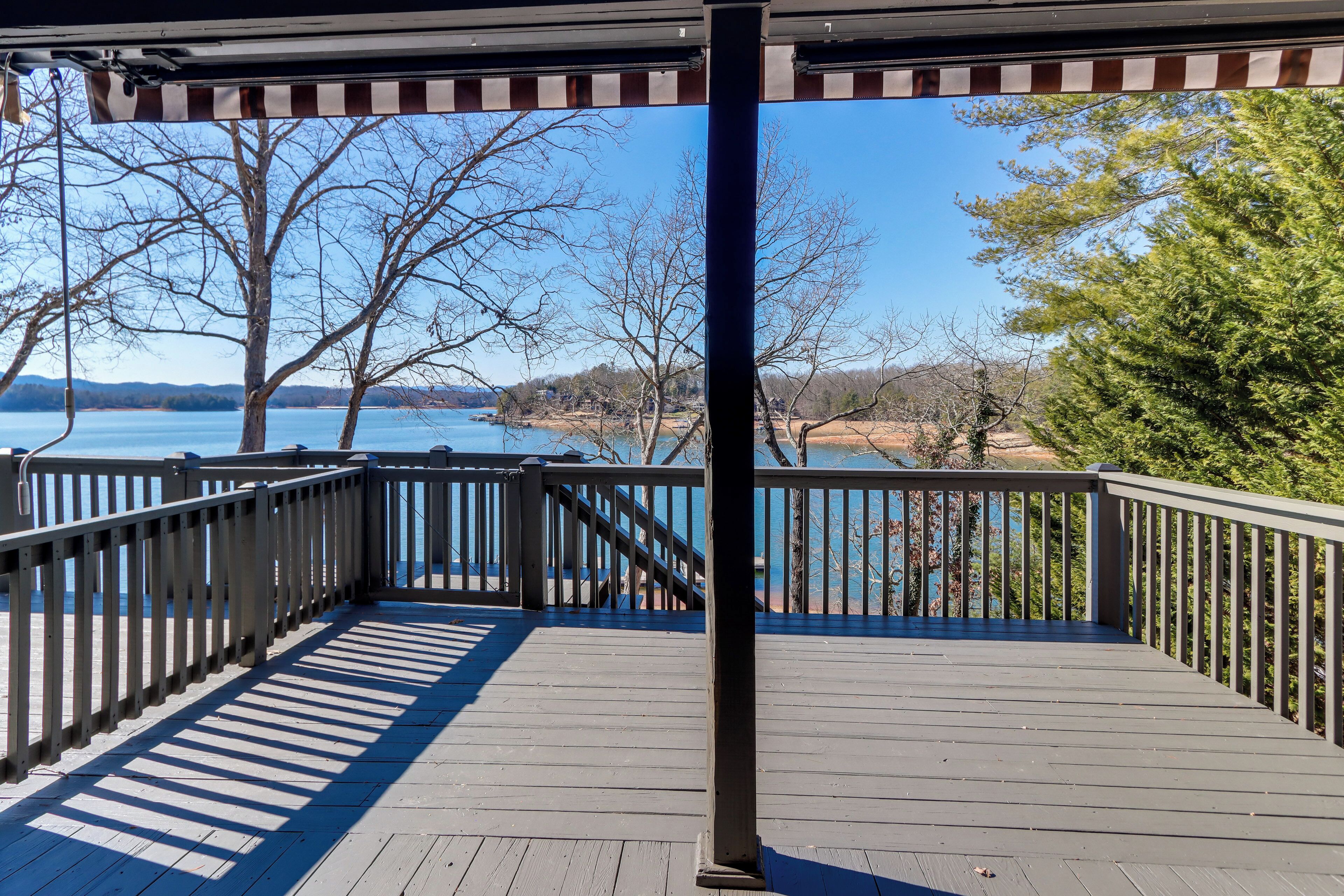 A wooden deck with a railing overlooking a body of water and trees.