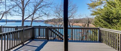 A wooden deck with a railing overlooking a body of water and trees.