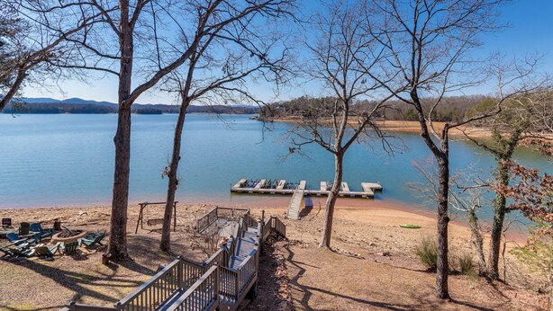 A lakeside view with a dock, lounge chairs, and a wooden deck. - Lakefront Townhome w/ Dock: 6 Mi to Blue Ridge! (Morganton)