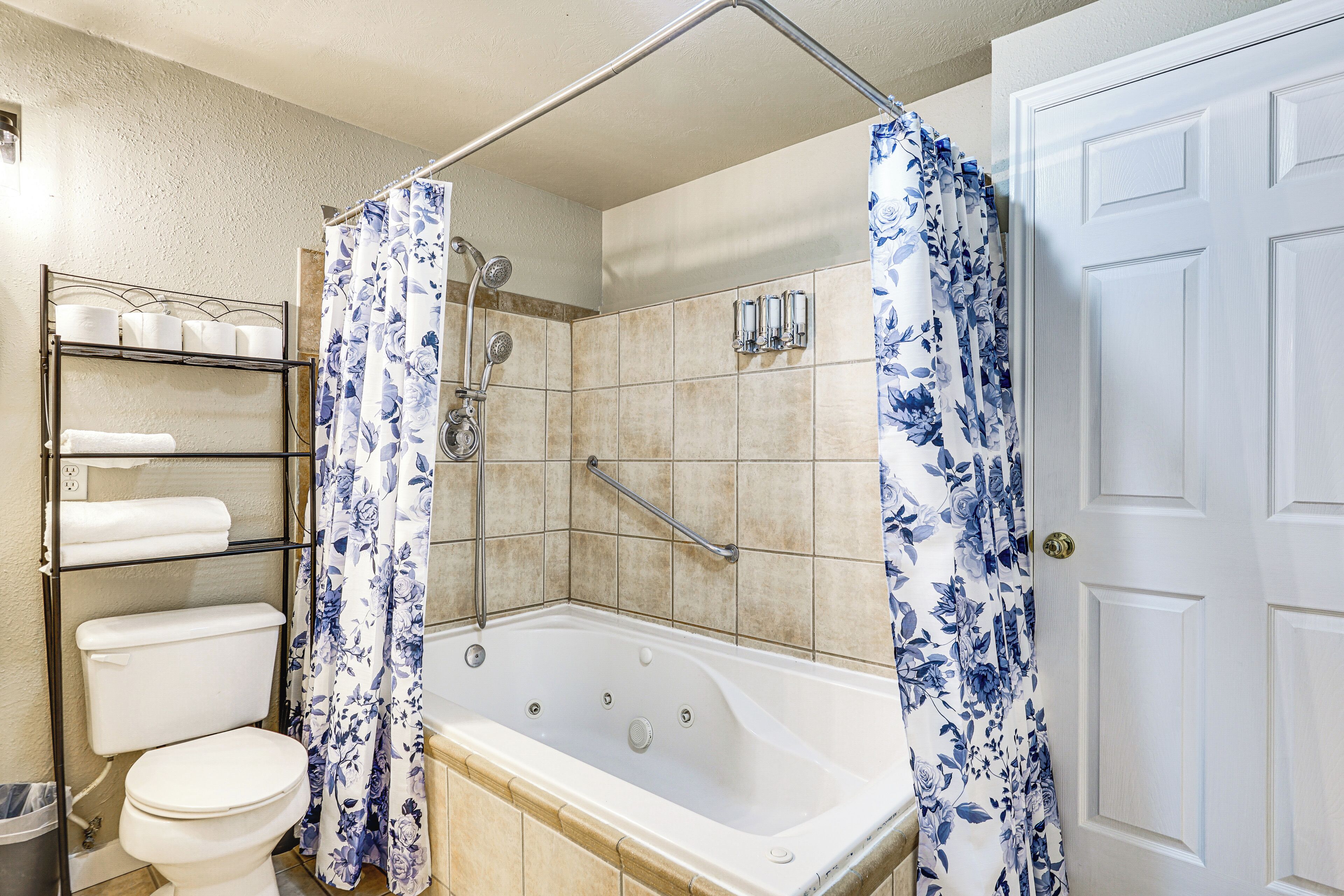 Une salle de bain équipée d’une baignoire, d’une douche, de toilettes et d’étagères où sont rangés les produits de toilette.