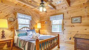 A wooden cabin bedroom with a bed, nightstands, a wooden dresser, and a ceiling fan. - Quaint Dahlonega Cabin w/ Cavenders Creek Access! (Dahlonega)