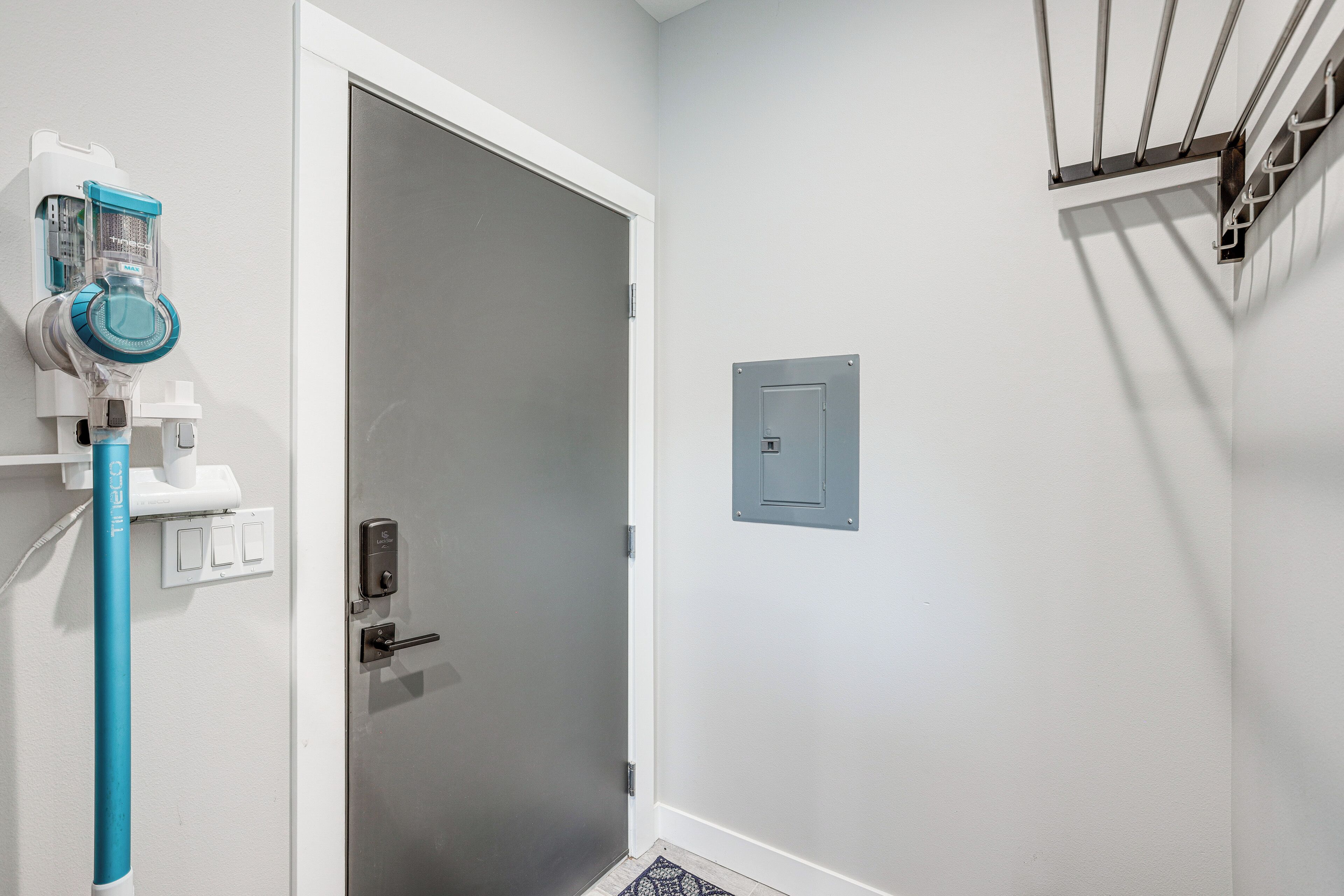 A bathroom with a white door, a towel rack, a towel dispenser, and a light switch.