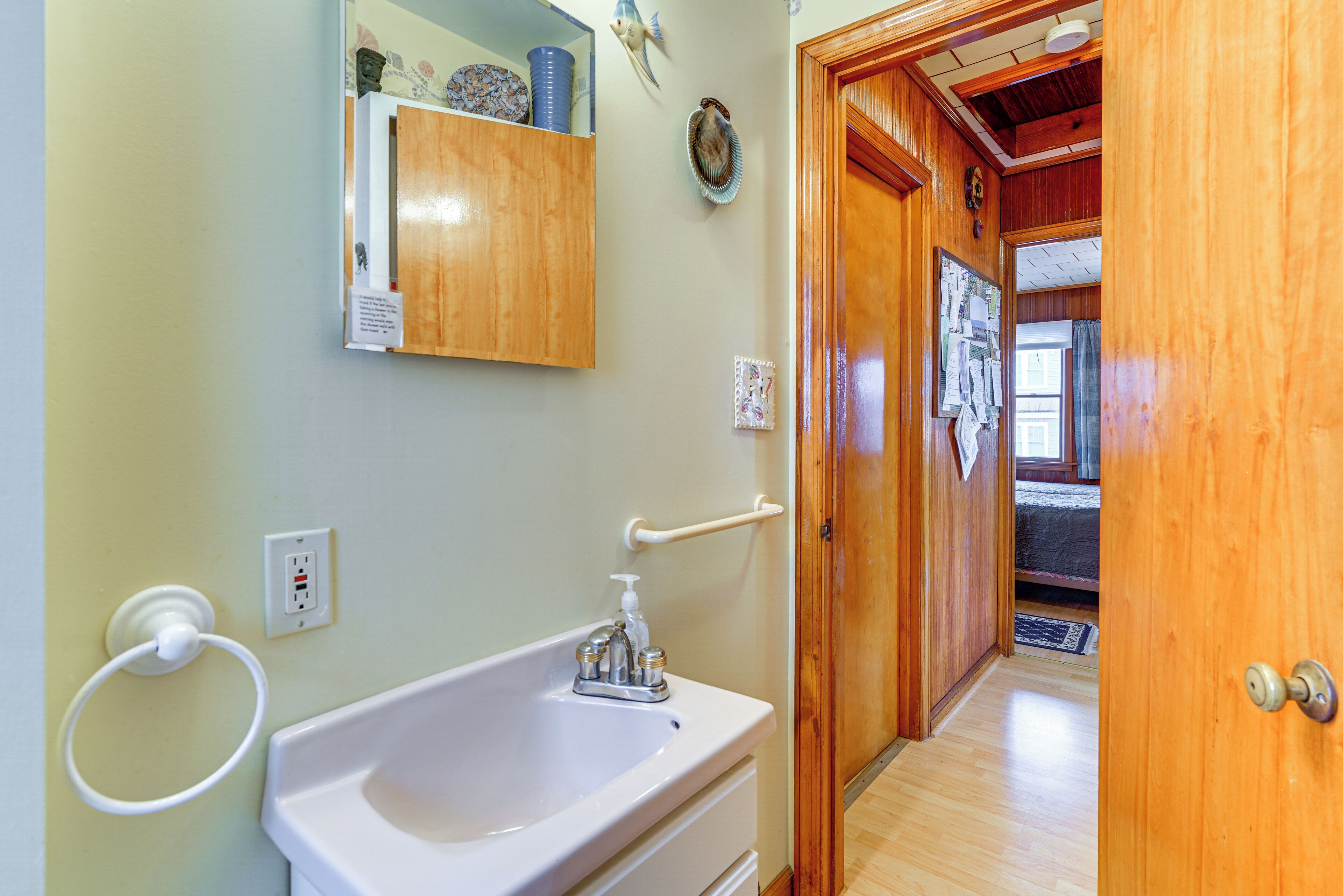 Une salle de bain avec un lavabo, un porte-serviettes et une porte en bois donnant sur une chambre.