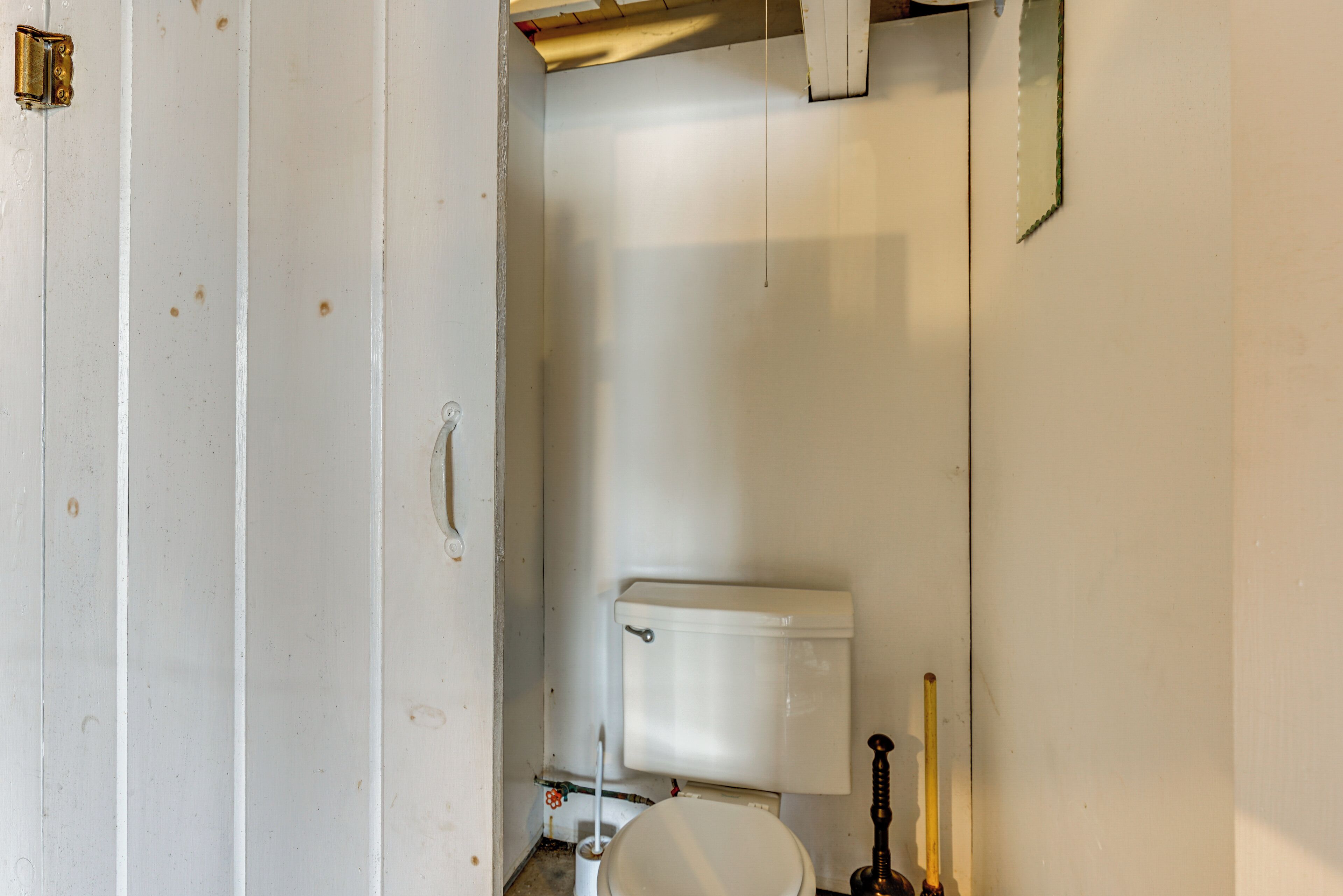 Et lille, simpelt badeværelse med toilet, bidet og toiletbørste.