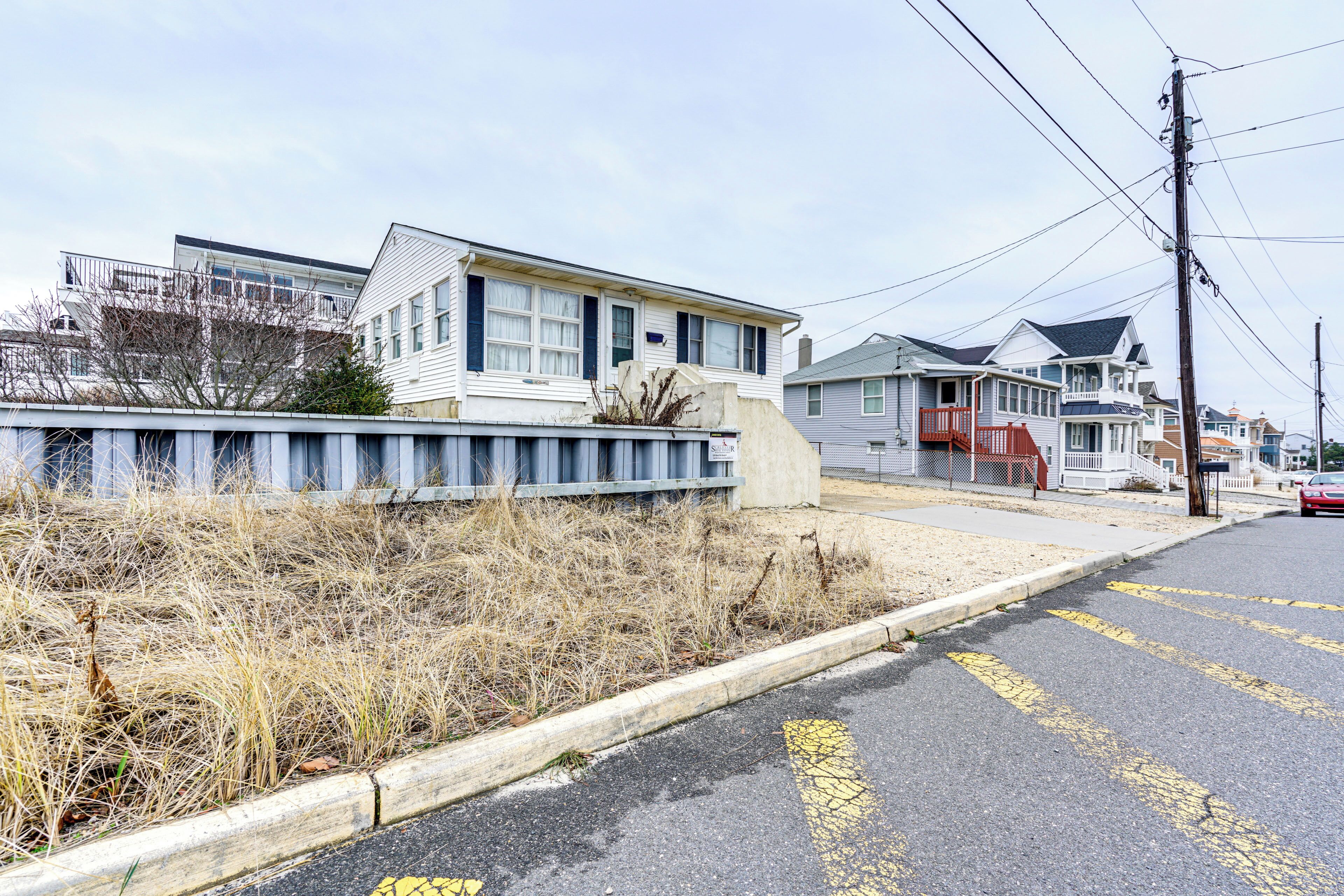 A residential street with houses, a sidewalk, and a curb.