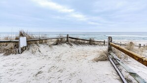 Ein sandiger Strand mit einer Holzlattenzaun und einem weißen Schild.