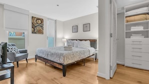 A bedroom with a bed, a desk, a chair, a wardrobe, and a door leading to another room. - 2br Furnished Apartment Near Smithsonian 2 Bedroom Apts by RedAwning (Washington)