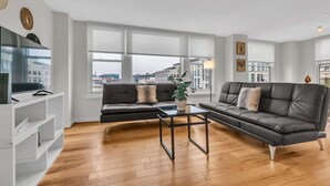 A modern living room with a sofa, a coffee table, and a TV on a stand. - 2br Furnished Apartment Near Smithsonian 2 Bedroom Apts by RedAwning (Washington)