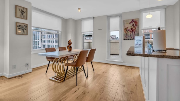 Eine moderne Küche mit Holzarbeitsplatte, einem Essbereich mit Tisch und Stühlen sowie großen Fenstern mit Blick auf die Stadt.