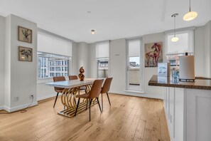 Enjoy meals in a stylish dining area with a city view, framed artwork, and a comfortable table for four.