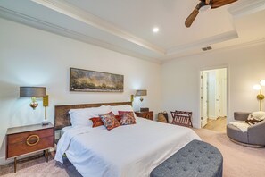 A well-lit bedroom with a large bed, bedside lamps, a wooden headboard, a painting, and a view of the hallway. - Brooksville Home ~ 12 Mi to Cabot Citrus Farms (Brooksville)