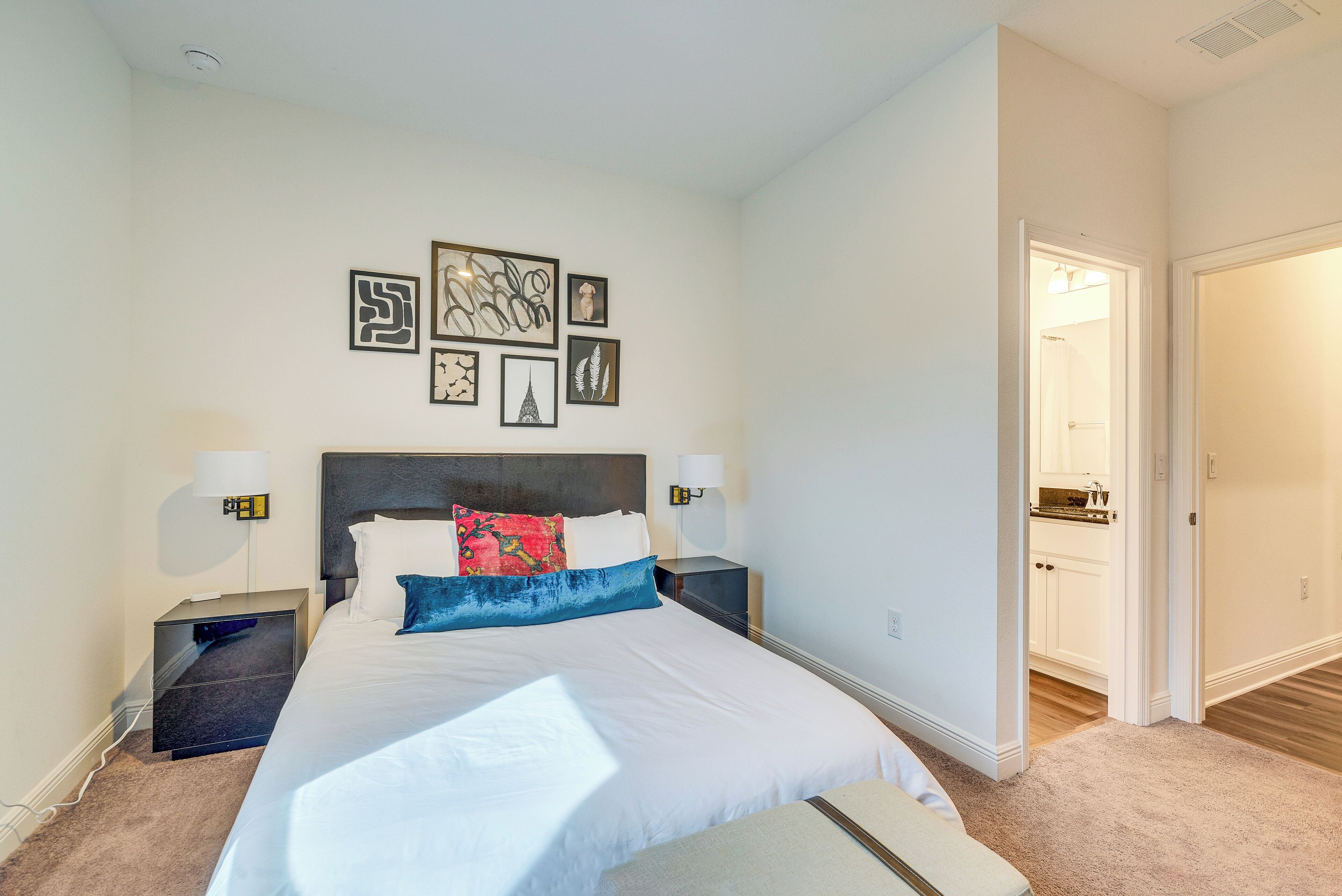 A neatly arranged bedroom with a large bed, bedside tables, and wall art.