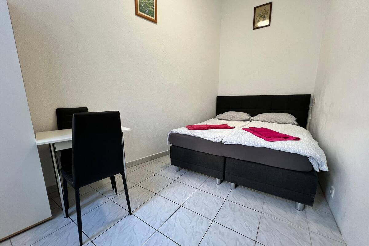 A bedroom with a bed, a desk, and a chair.